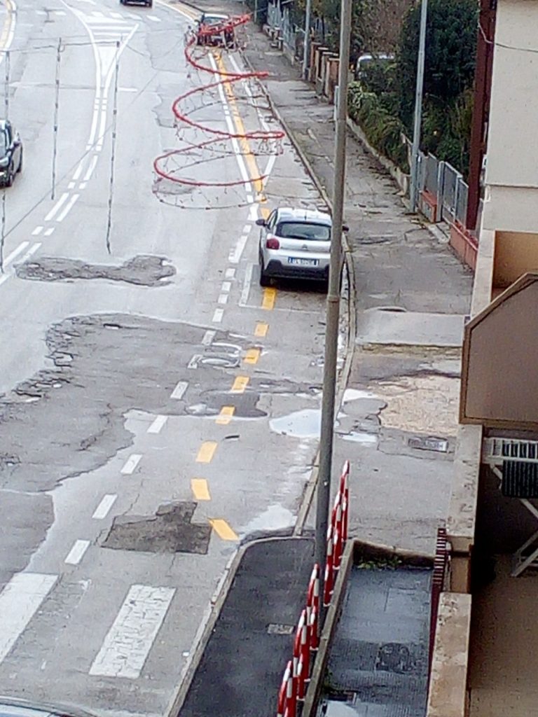 Dopo la sopraelevata la pista continua, delimitata dalle strisce gialle, là dove ci sono parcheggi auto