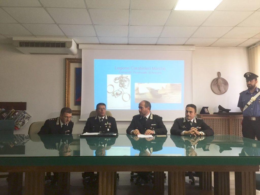 I carabinieri mentre illustrano i dettagli dell'arresto, sullo sfondo i gioielli della vittima e il coltello sequestrato in casa