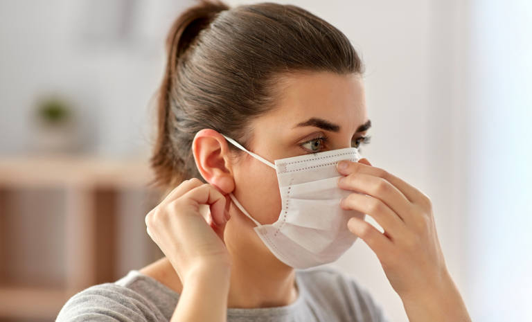 health, safety and pandemic concept - young woman wearing protective medical mask