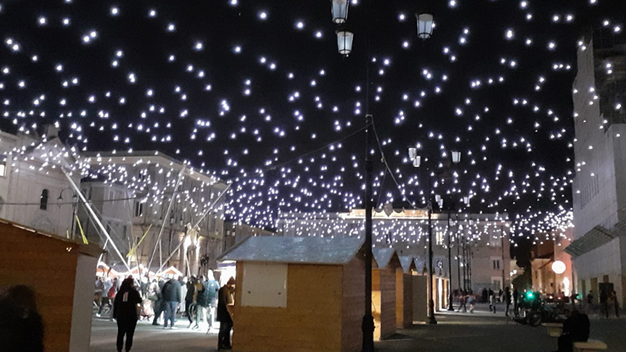 Villaggio di natale con mercatino e pista sul ghiaccio e cielo stellato in piazza Garibaldi